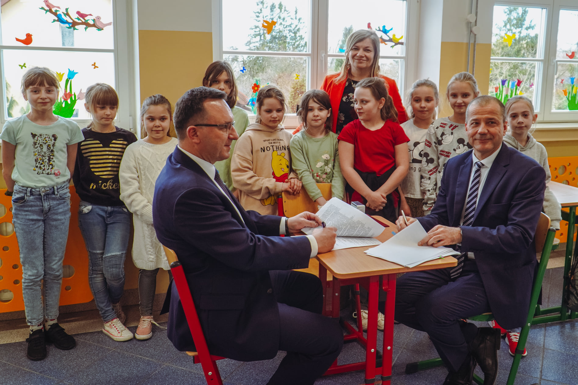 Burmistrz Miasta Tomasz Sielicki i Prezes Wodociągów Miejskich podpisują umowę za nimi stoją dzieci ze Szkoły Podstawowej Nr6